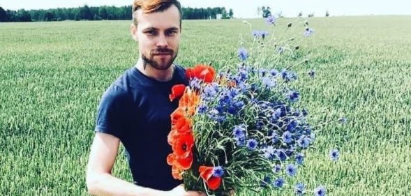 Normunds Kindzulis holds a bouquet of flowers in a field