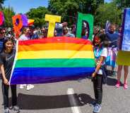 Two girls lead a segment of the parade with a rainbow flag followed by adults with the word 'PRIDE' during the Portland Pride Parade
