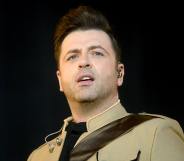 Mark Feehily of Westlife persons on stage in a light brown jacket