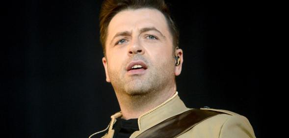 Mark Feehily of Westlife persons on stage in a light brown jacket