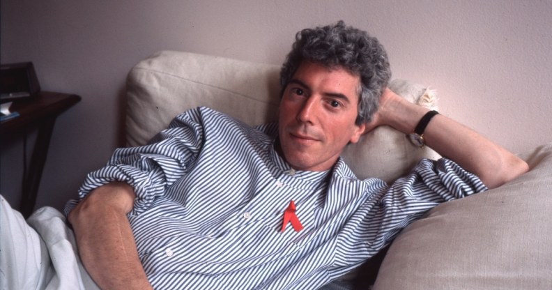 Patrick O'Connell sitting on his bed in a blue shirt and red ribbon