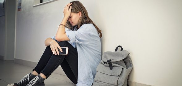 Distressed LGBT+ student targeted by bullies sits with her head in her hands