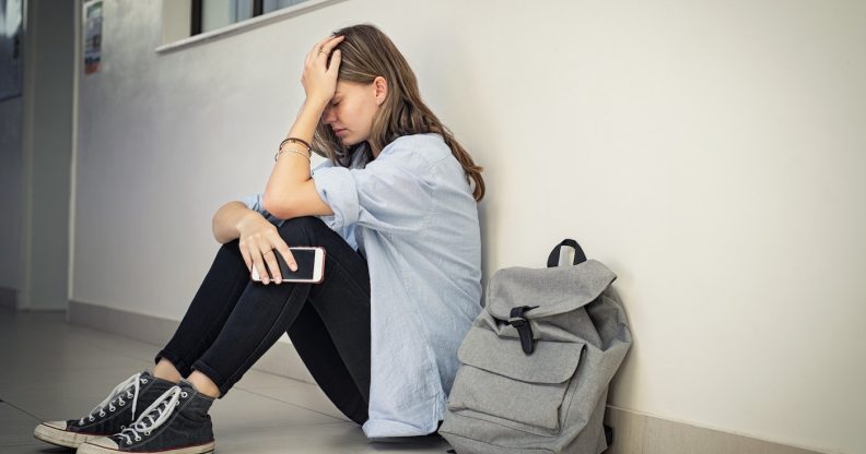 Distressed LGBT+ student targeted by bullies sits with her head in her hands