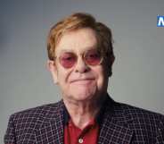 Elton John smiles against a grey background