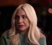 Lady Gaga emotionally looks to the side in a green jumper