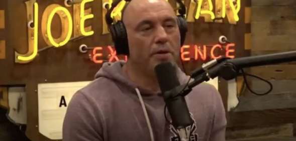 Joe Rogan in a hoodie behind the microphone