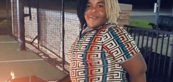 Thomas Hardin stands outside in a printed dress