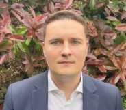 Wes Streeting wearing a shirt and blazer in front of a bush