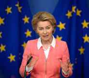 President of the European Commission Ursula von der Leyen holds a press conference in a pink zip-up jacket agains the EU flag