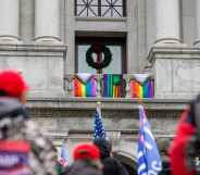 Flags are seen hanging from the balcony outside of Pennsylvania lieutenant governor John Fetterman's office as pro-Trump demonstrators rally below, Supporters of President Donald Trump urged legislators to decertify the election