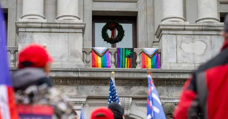 Flags are seen hanging from the balcony outside of Pennsylvania lieutenant governor John Fetterman's office as pro-Trump demonstrators rally below, Supporters of President Donald Trump urged legislators to decertify the election