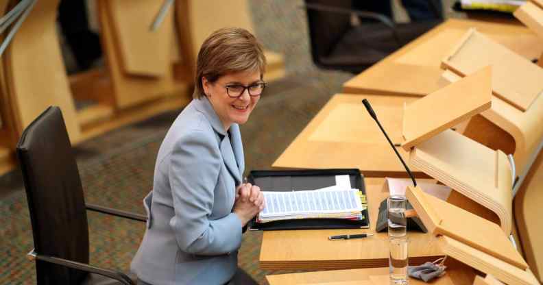 Nicola Sturgeon sits down in Holyrood in a blue pant suit