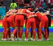 Denmark players form a circle in front of a rainbow advert during the UEFA Euro 2020 Championship Round of 16 match between Wales and Denmark