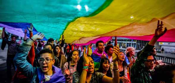 People hold up an LGBT+ Pride flag during a march