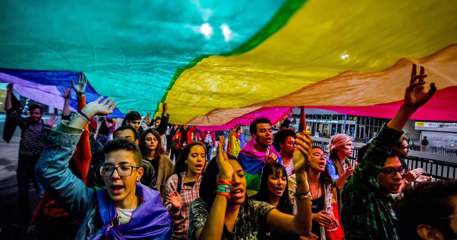 People hold up an LGBT+ Pride flag during a march