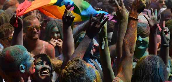 A woman brandishes a Rainbow flag during a Holi Party before the Gay Pride Parade in Barcelona