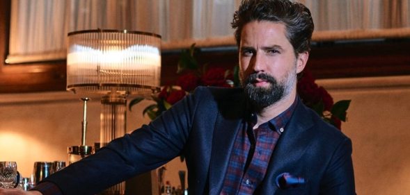 Jack Guinness lounges on a leather chair in a dimly-lit office