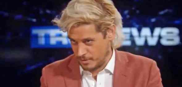 Milo Yiannopoulos looks down while wearing a shirt and blazer