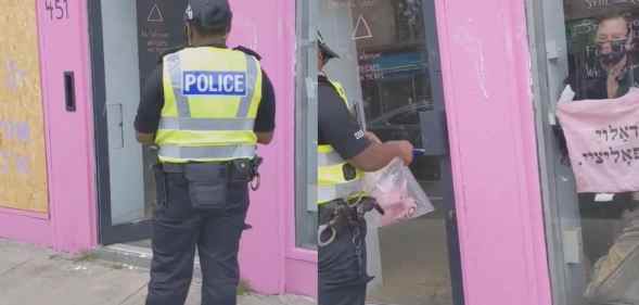 Police seizing a "f**k the police" tote bag as evidence from the queer, anarchist Jewish cafe Pink Peacock