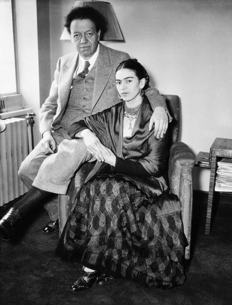 This is a black and white image of the artist Frida Kahlo posing with Diego Rivera.