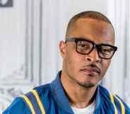 T.I. looks to the camera in a blue bomber jacket and black glasses
