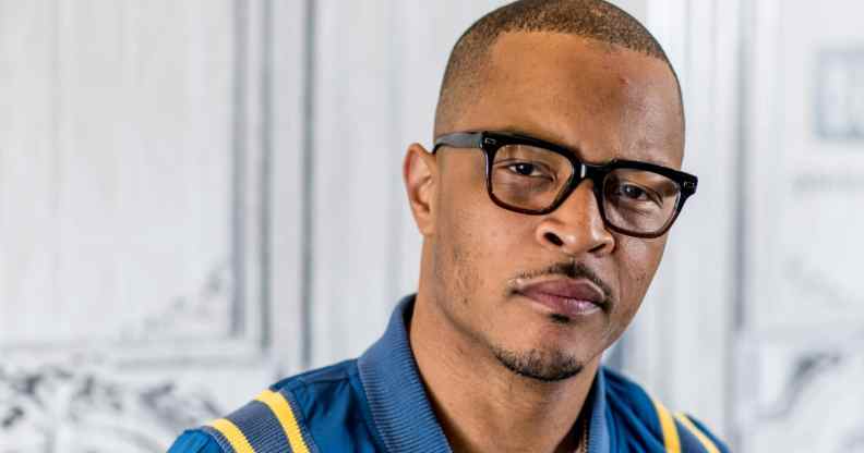 T.I. looks to the camera in a blue bomber jacket and black glasses