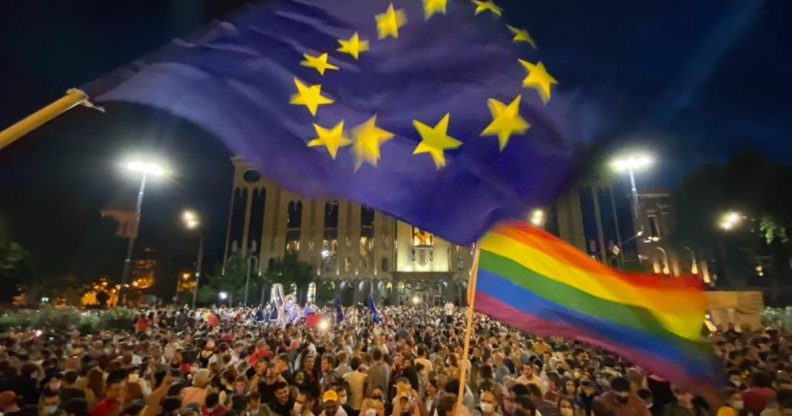 Thousands in front of the Georgian Parliament Building waving LGBT+ Pride flags