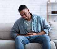 A Black man having a painful stomach ache, caressing his tummy