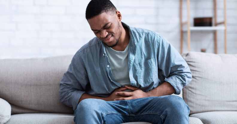 A Black man having a painful stomach ache, caressing his tummy