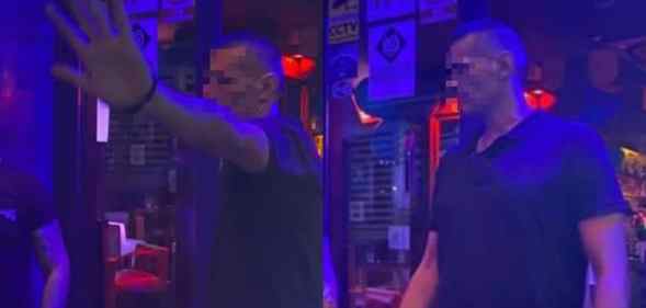 A bouncer tries to stop his photograph being taken at a dimly-lit bar