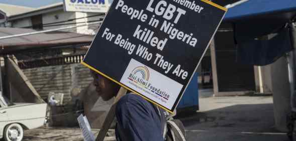 A young man holds a sign remembering the murders of LGBT+ people in Nigeria