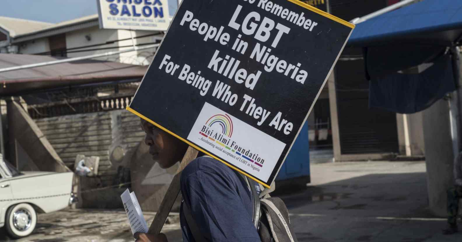 A young man holds a sign remembering the murders of LGBT+ people in Nigeria
