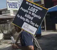 A young man holds a sign remembering the murders of LGBT+ people in Nigeria