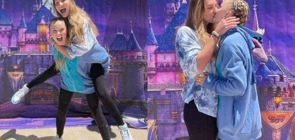 JoJo Siwa and Kylie Prew are seen having fun and sharing a kiss in front of a Disney backdrop with colourful Mickey Mouse balloons