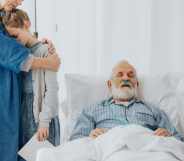 A family stands around their grandfather as he lies dying in a hospital bed