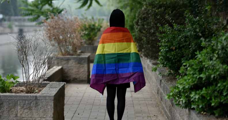Student with LGBT+ flag draped over their shoulders, photographer from behind, in Beijing, China