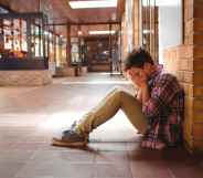 Sad schoolboy sitting alone in corridor