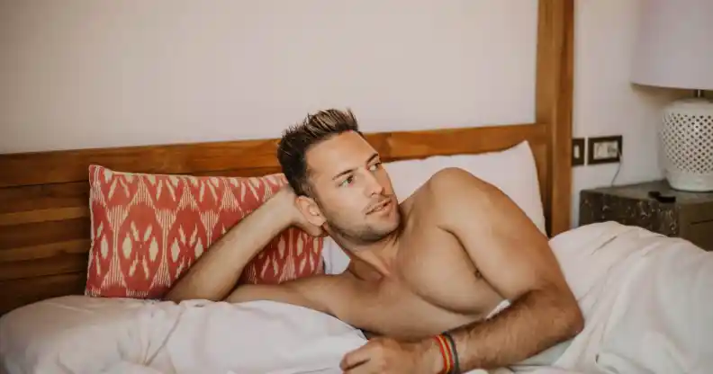 Shirtless sexy male model lying alone on his bed in his bedroom.Carefree guy enjoying new day.