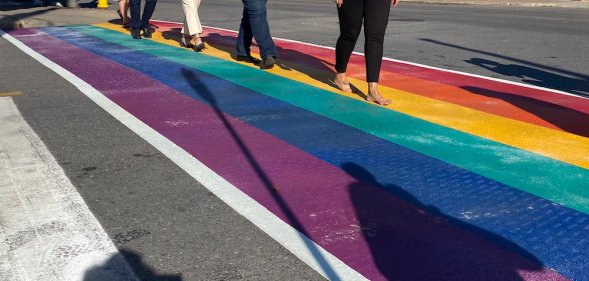 People walk across a rainbow road crossing in Port Colborne, Canada