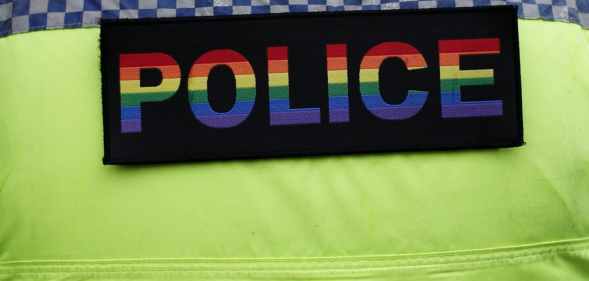 A police officer wears a pride coloured police badge on his uniform