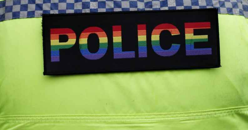 A police officer wears a pride coloured police badge on his uniform