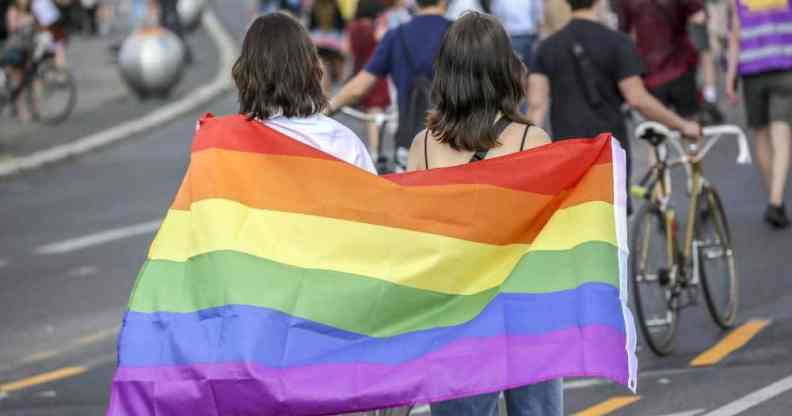 Two women hold the rainbow pride flag as they take part in the Queerschutz Now march in Berlin, Germany