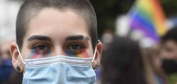 A protester with the face painted in the LGTBQ flag colours