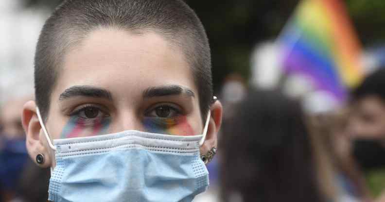 A protester with the face painted in the LGTBQ flag colours