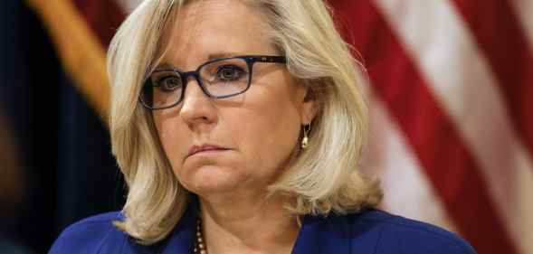 Liz Cheney in a blue jacket against the US flag