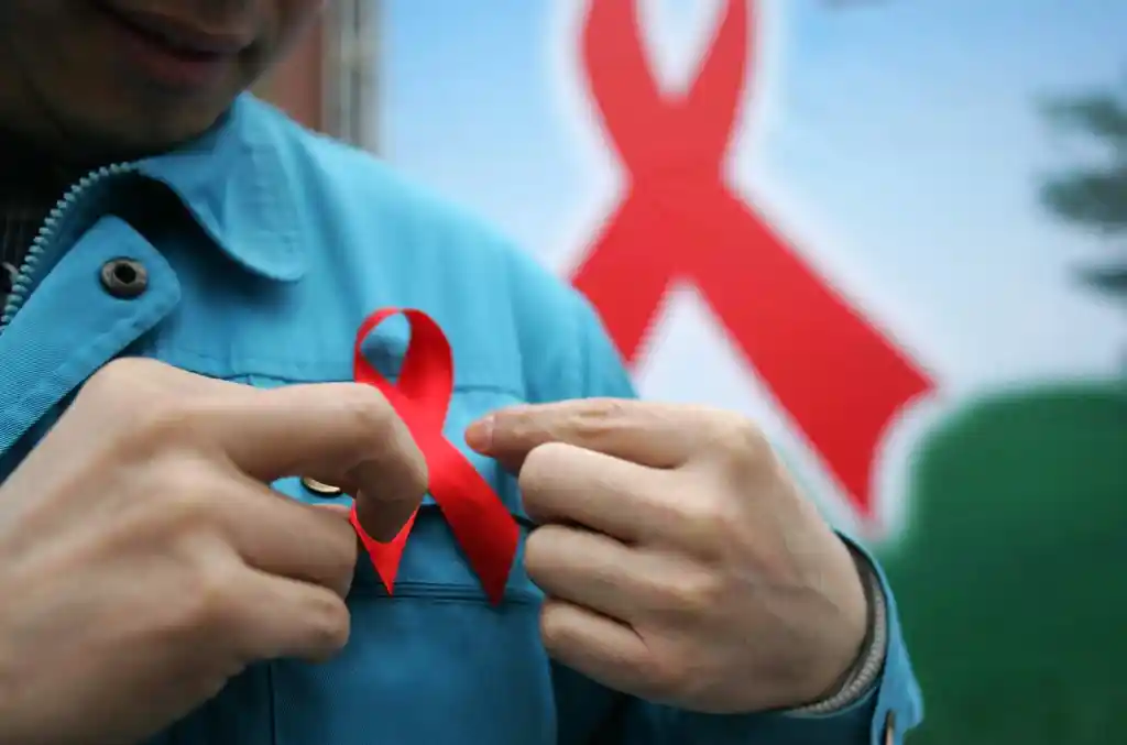 A photo of a person putting on a red ribbon for HIV AIDS awareness on World AIDS Day