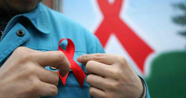 A photo of a person putting on a red ribbon for HIV AIDS awareness on World AIDS Day