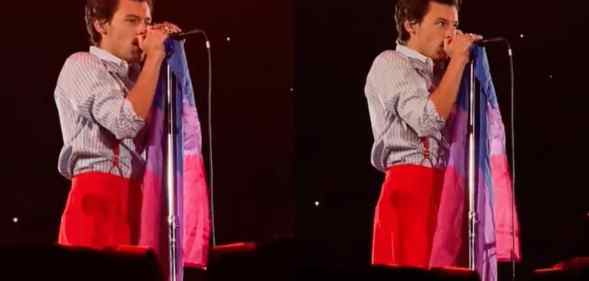 Harry Styles holds a bi Pride flag on stage