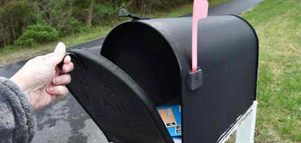 A person opening up a mailbox to illustrate trans and non-binary people from Canada seeing their deadname on voters cards in the mail