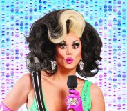 Manila Luzon holding a microphone in front of a sequinned backdrop